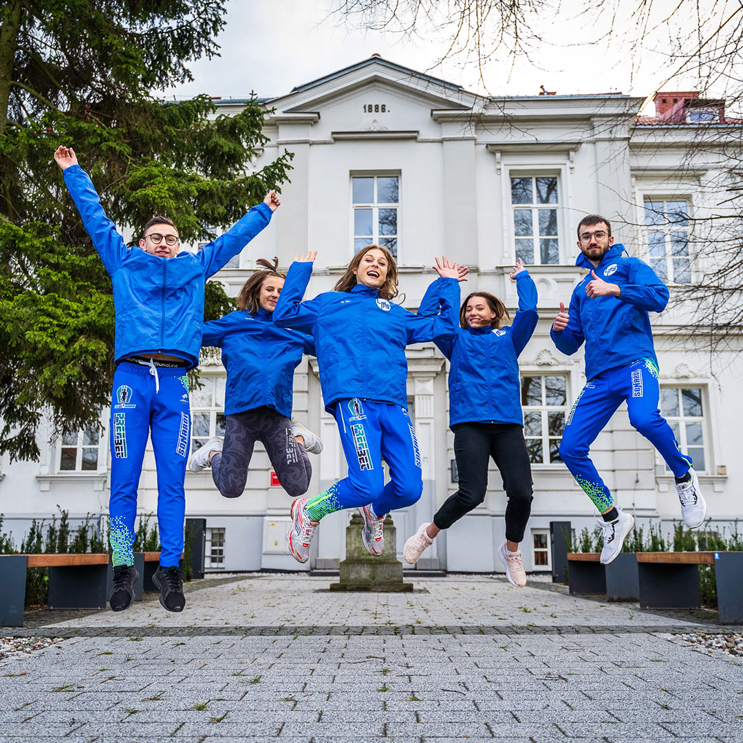 Uczniowie podskakują. W tle budynek szkoły.